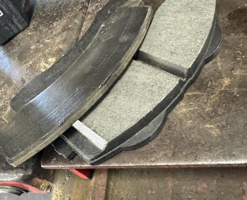 Worn brake pad next to a new brake pad